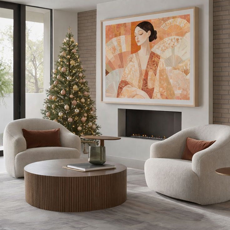 Modern living room with two armchairs, a coffee table, and a Christmas tree. A large figurative wall art hangs above the fireplace.
