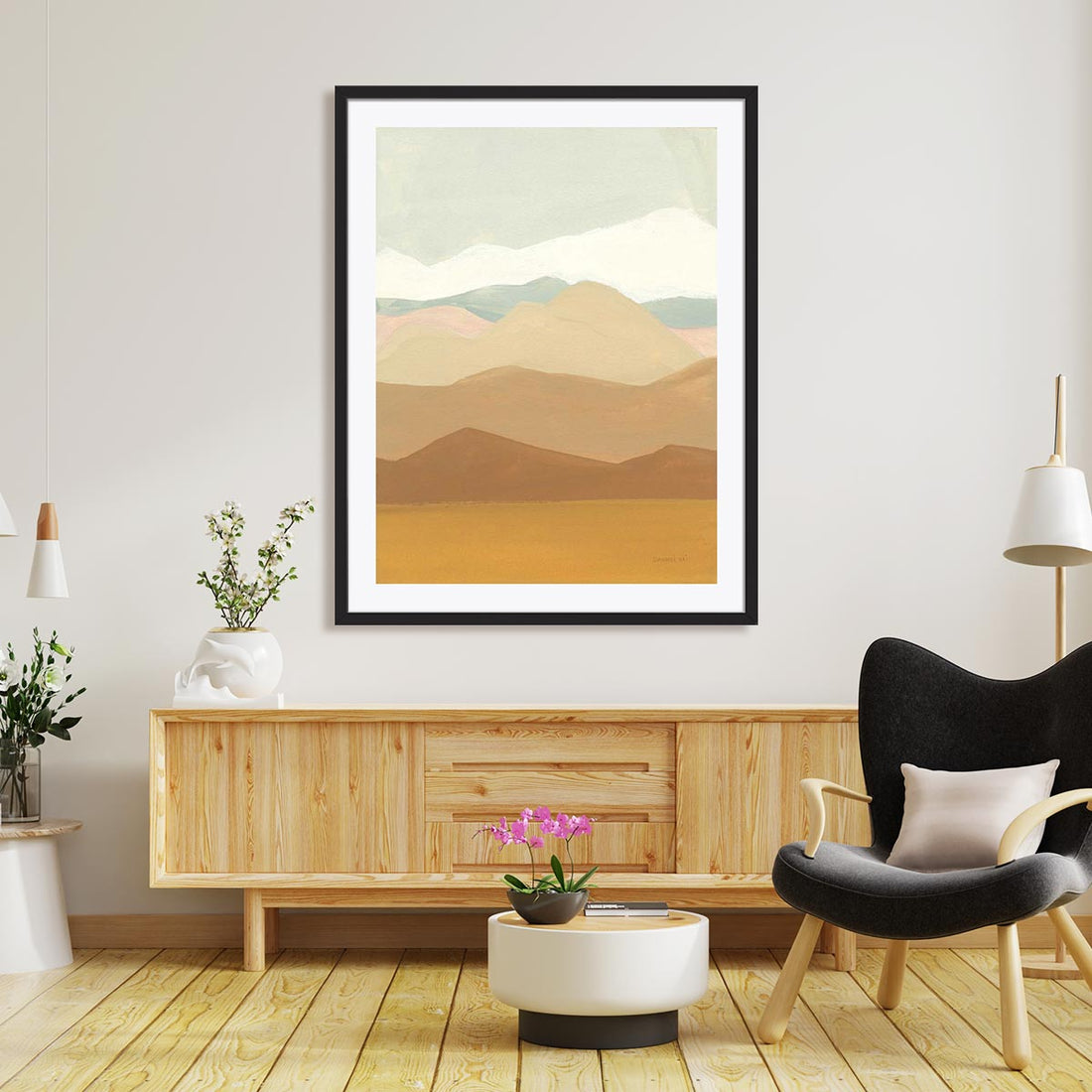 large wall art in black frame above a console table. There is a lounge chair in front.