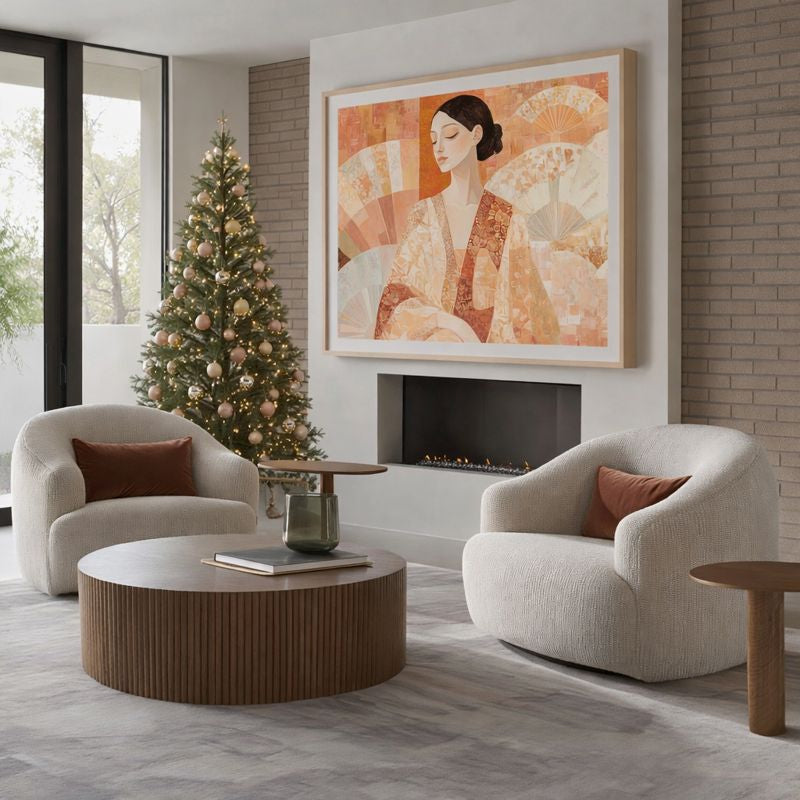 Modern living room with two armchairs, a coffee table, and a Christmas tree. A large figurative wall art hangs above the fireplace.